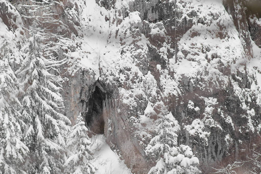 在白雪皑的高山岩石悬崖上的洞穴图片