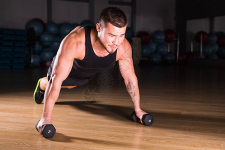 健身房男子俯卧撑力量俯卧撑锻炼与哑铃在健身锻炼图片