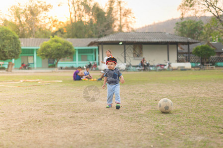 小亚洲男孩在球场上踢足球图片