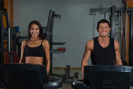 苗条的女人和肌肉男教练在体育健身房图片