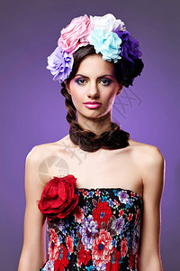 有紫色眼影和粉红嘴唇的美丽的年轻女子头顶有鲜花的发图片