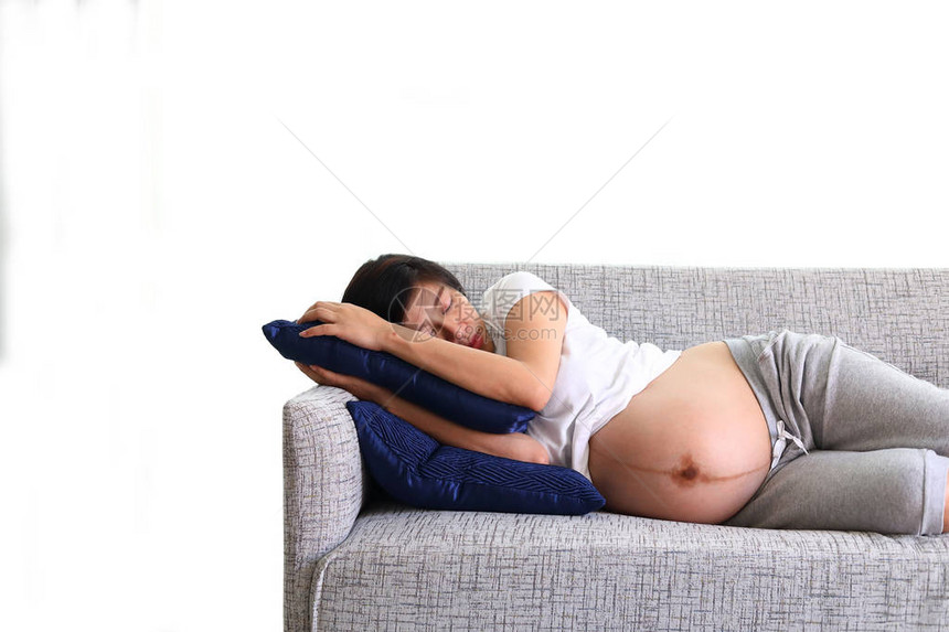 在家庭客厅沙发家具上睡着甜美梦的美丽的孕妇图片