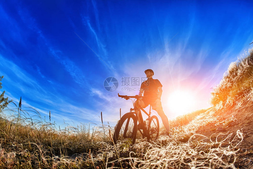 日出时骑山地自行车站在小路上的低角度视图有吸引力的运动员在运动服和头盔水平照片和鱼眼在乡村图片