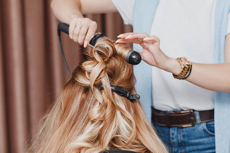 在美容院使用铁卷发器做发型的女理发师图片