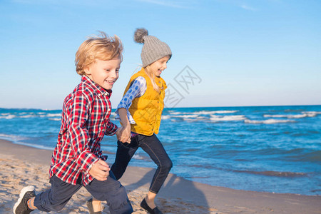 两个有趣的白人儿童朋友在日落时在海洋沙滩上玩耍的集体肖像图片