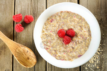 早餐一碗燕麦粥和草莓木制背景图片