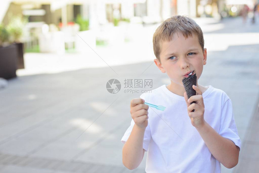 快乐的小男孩在市中心吃冰淇淋图片