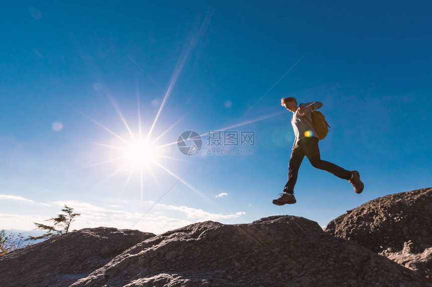 男子在登山时跳过高处的缝隙图片