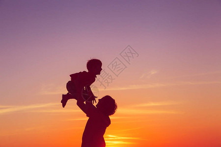 父亲和小儿子剪影在夕阳的天空玩耍图片
