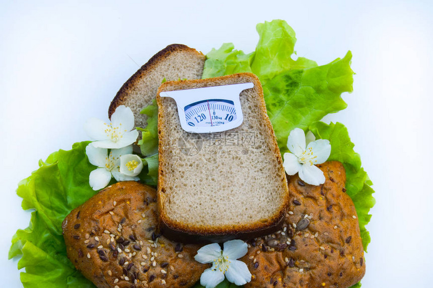 从在白色背景上隔离的一片面包的假想鳞片健康饮食和体重管理的饮食概图片