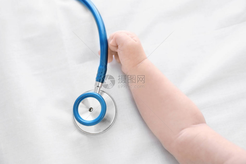 婴儿手和床单上的听诊器婴儿健康概念图片