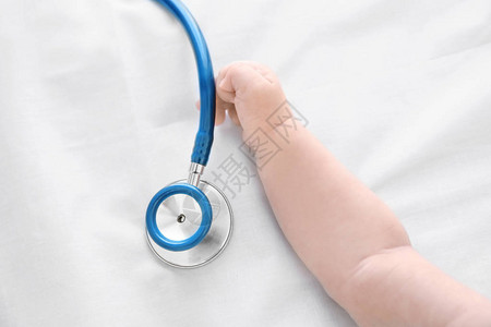 婴儿手和床单上的听诊器婴儿健康概念图片