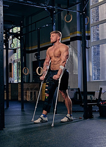 穿着拐杖的不穿衣服的健美运动员在健身房里站图片