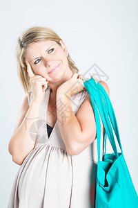 有购物袋摆在的美丽的沉思年轻白肤金发的孕妇图片