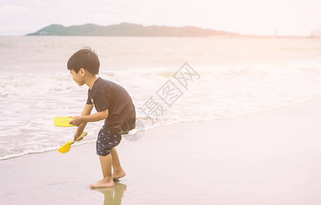 男孩在沙滩上玩沙子和波浪图片