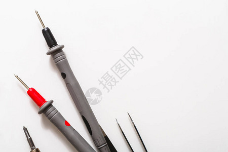 白色背景上的工具特写螺丝刀镊子和万用表探头特写维修和测量工图片