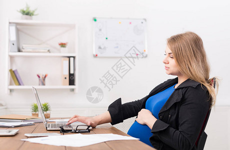 孕妇在办公室的笔记本电脑上工作图片