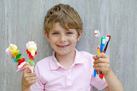 另一只手拿着牙刷孩子用不同的不健康的五颜六色的糖果健康食品图片