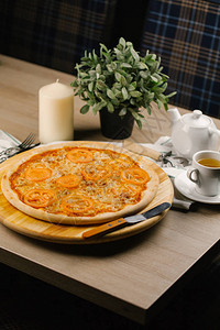 在桌子上的圆形木板上放着西红柿和香草的奶酪披萨图片