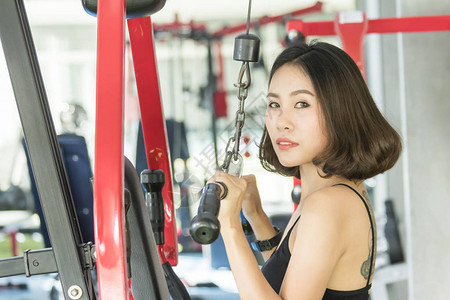 在健身俱乐部锻炼肌肉的亚裔妇女图片