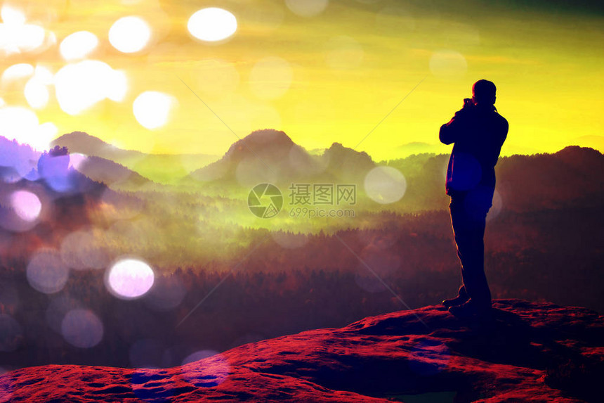 摄影师在岩石高峰用大照相机拍摄照片梦幻的雾色风景图片