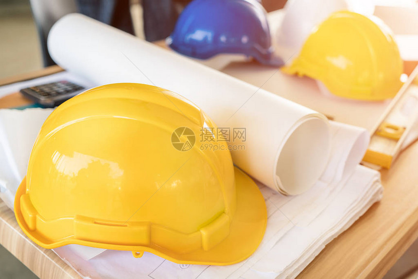 建筑工程师黄色头盔计算器水平和办公桌上的项目图纸图片