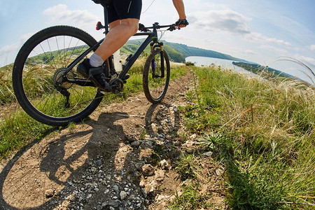 年轻的骑自行车者骑山地自行车穿过绿色草地图片