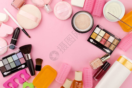 平躺粉红色背景上的不同化妆美容护理必需品化妆品图片