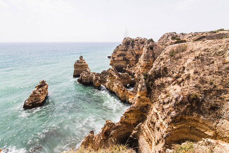 旅行到令人惊叹的岩石悬崖上沙地卡米洛海滩上有海洞在多彩的阳光图片