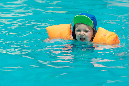 婴儿游泳在蓝泳池水图片