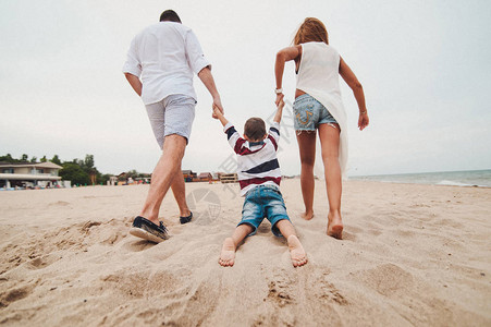 快乐的年轻家庭在沙滩上玩得开心图片