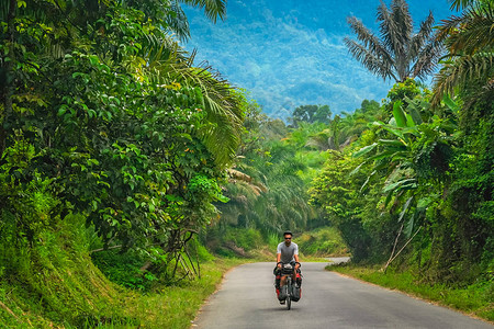 在印度尼西亚Sumbava岛茂密的丛林地貌中骑自行车的男图片