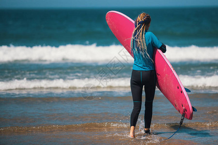 在海边有冲浪板的年轻女子图片