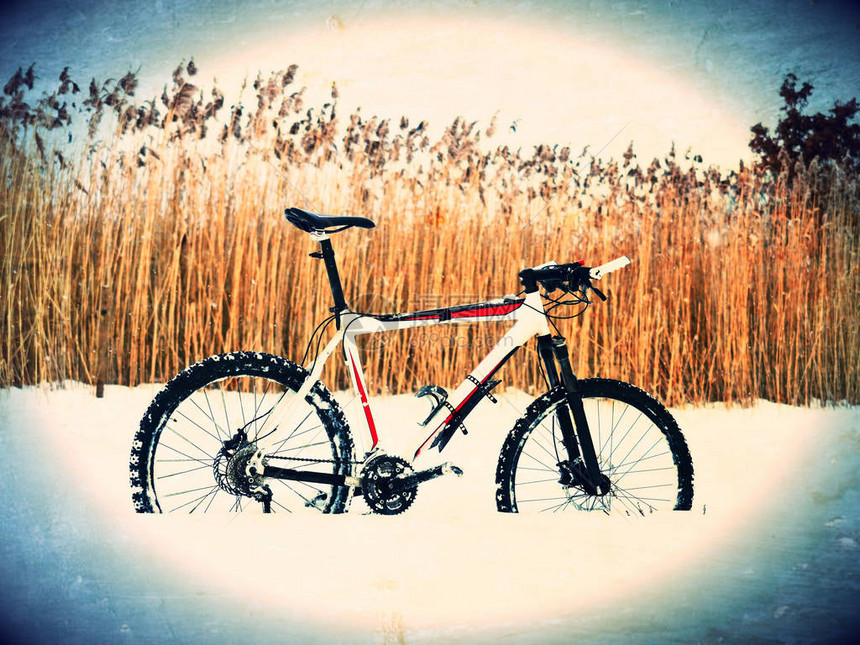 胶片颗粒效果山地自行车停留在粉雪中在深雪堆中迷失了道路后轮细节雪花融化在黑暗图片
