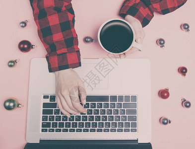 自由女郎手持笔记本电脑靠近咖啡杯和粉红背图片