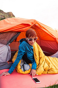 女孩躺在帐篷附近的一个睡袋里图片