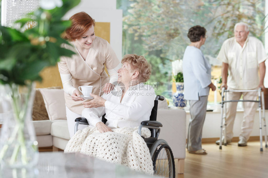 友善护士为在养老院轮椅的残疾妇女图片