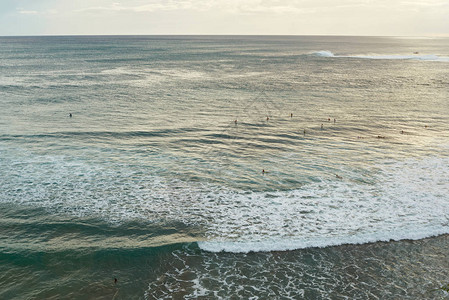 一群冲浪者在日落时分在海洋中等待波浪图片