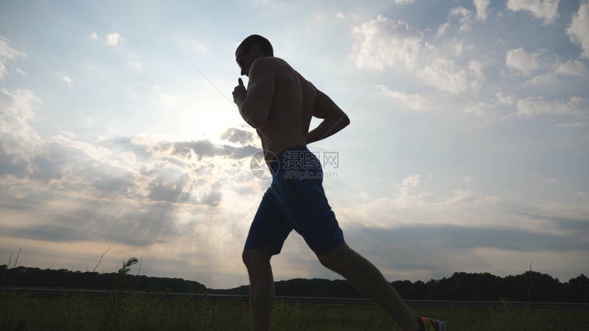 日落时分在乡间小路上慢跑的肌肉男的剪影马拉松跑户外男慢跑训练档案运动员在蓝天下锻炼和跑步运动和积图片