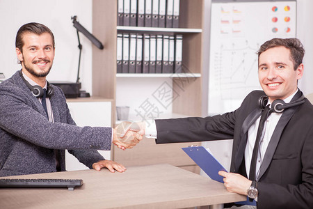 两名正式西装商人在公司办公室内行走时握手图片