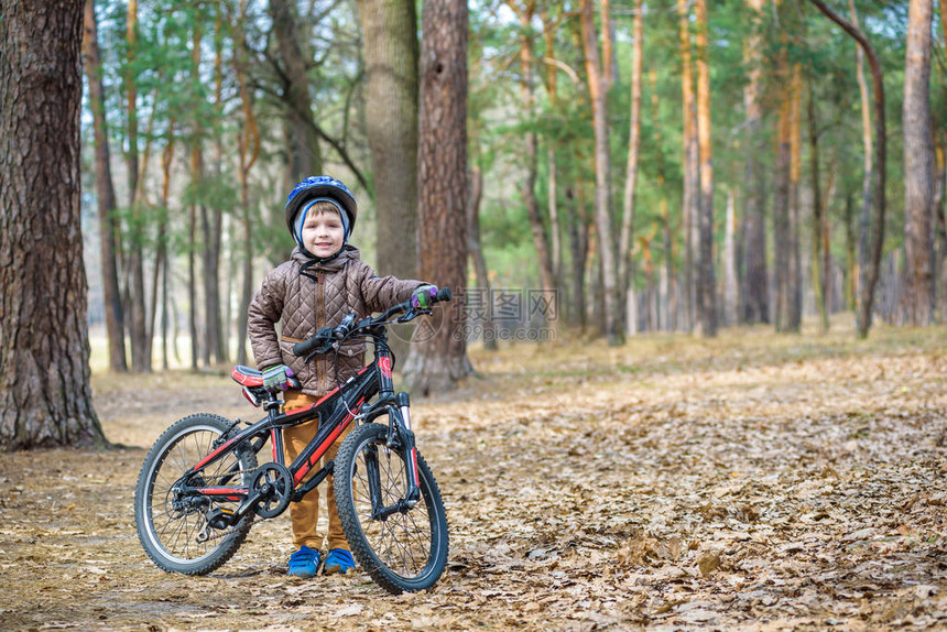 快乐的3或5岁男孩在美丽的秋日骑着自行车在秋天的森林里玩得开心活跃的孩子戴着自行车头盔安全运动休闲图片