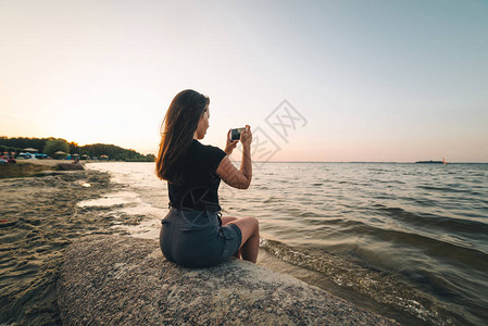 女人坐在海滩上拍摄图片
