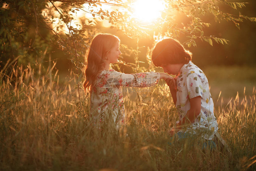日落时女孩和男孩坐在草地上男孩亲吻女图片