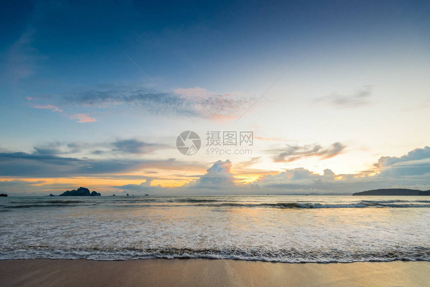 日落时美丽的海浪涌入沙滩图片