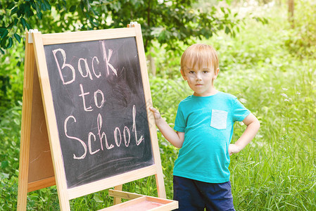 可爱的小男孩在户外的黑板上写字回图片