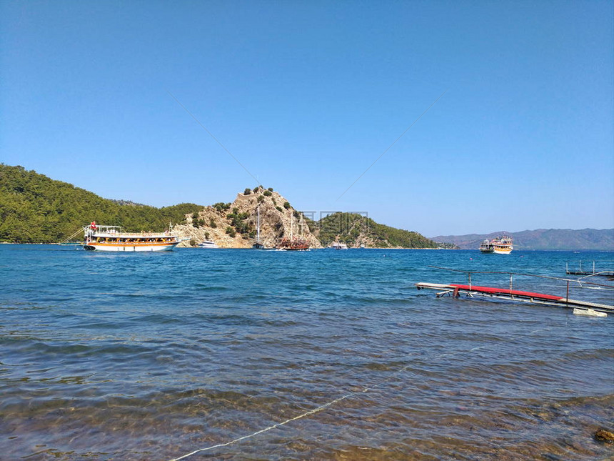 游艇在风景如画的丘陵海岸附近蓝色和绿色纯天然颜色水图片