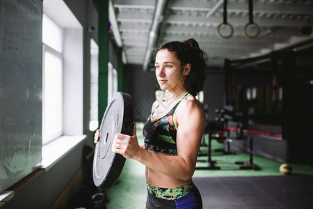 一个美丽肌肉发达运动型的女孩在手和背部的肌肉上进行锻炼在健身房的背图片