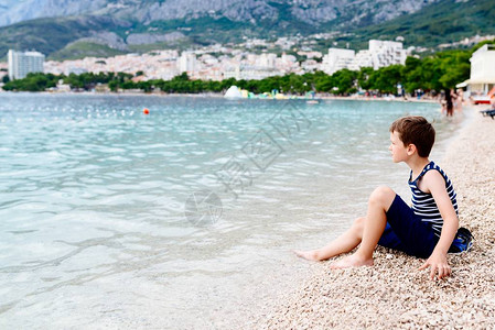 坐在沙滩上扔小石头的有图片