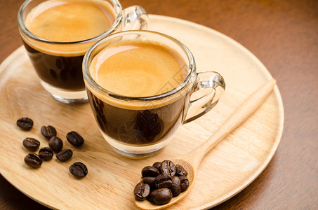 两杯咖啡和两杯烤咖啡豆放在木板上图片