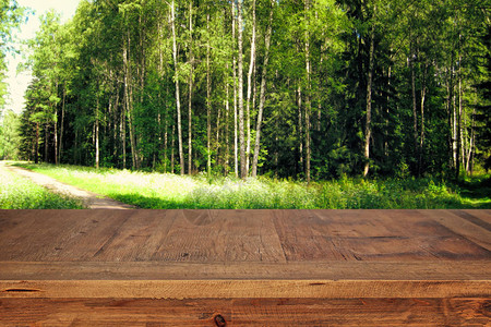 在前面的绿色森林树木景观背景的木桌的形象用于产图片